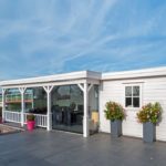 Lugarde Summerhouse SP53b is a big modern summerhouse with a flat roof. Its patio and sliding glass doors which cover two walls create a luxurious and innovative look. The adjoining closed room is ideal for storage.